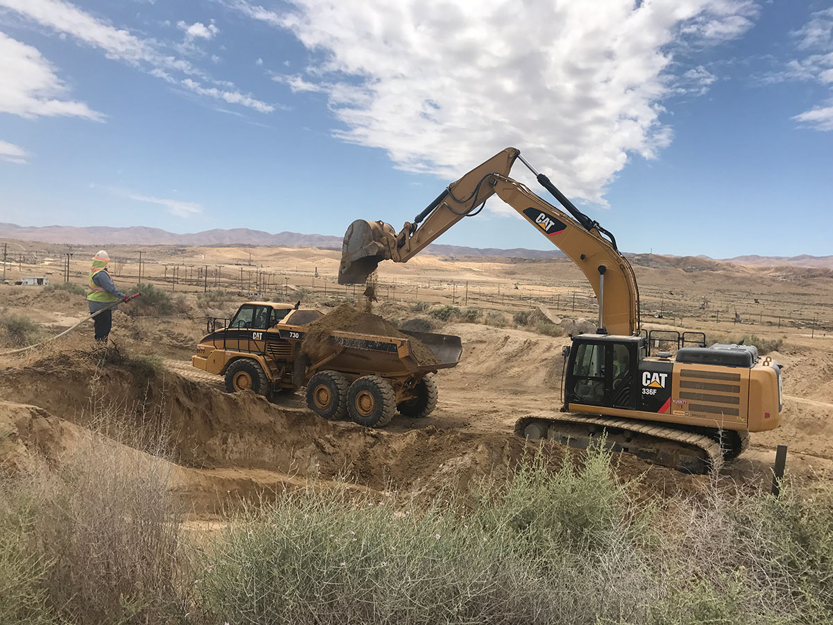 Excavator dumping dirt into dirt hauler