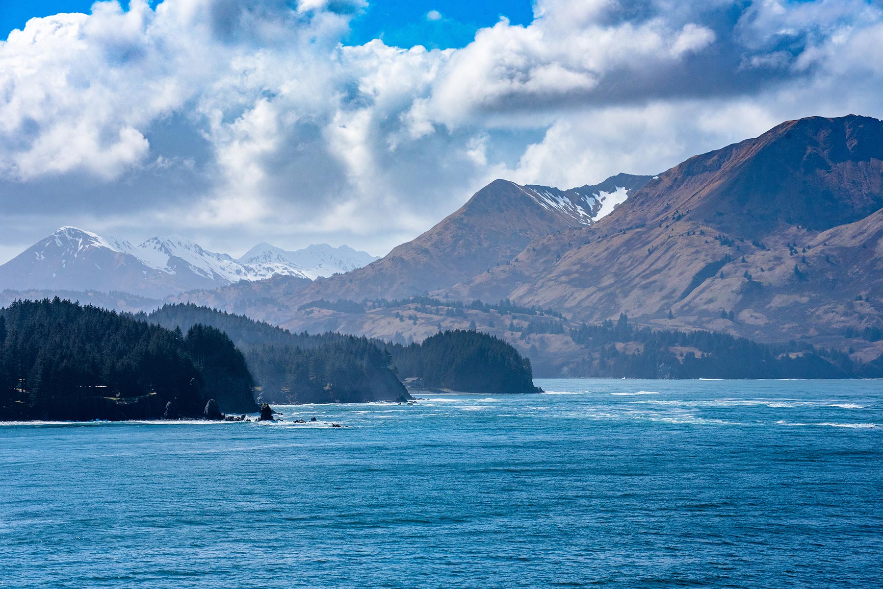 Mountains, trees, and rocks next to the ocean